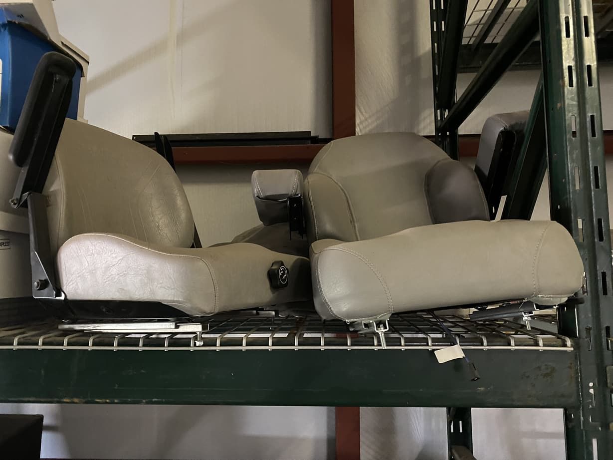 Two seats are sitting on top of a shelf in a warehouse.