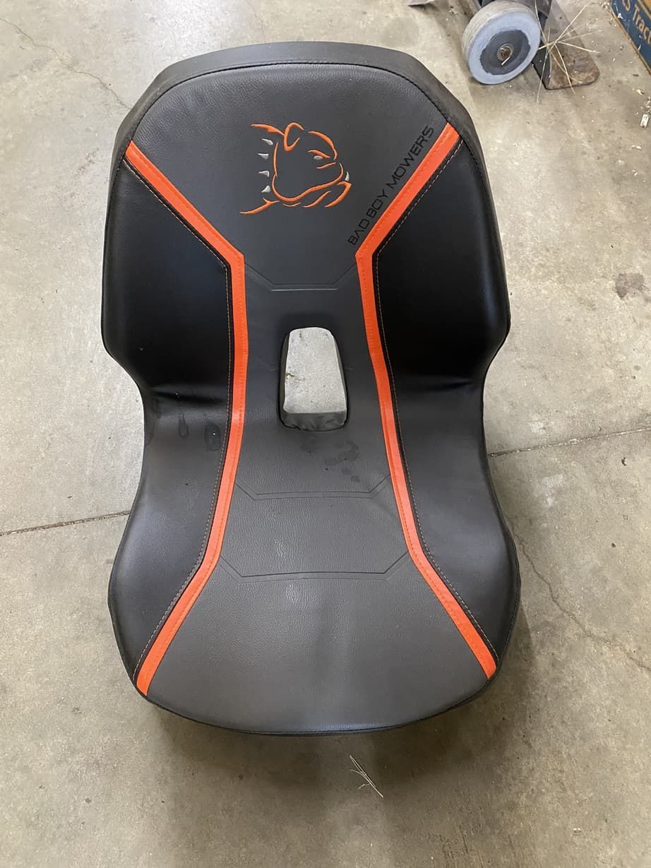 A black and orange chair is sitting on a concrete floor.