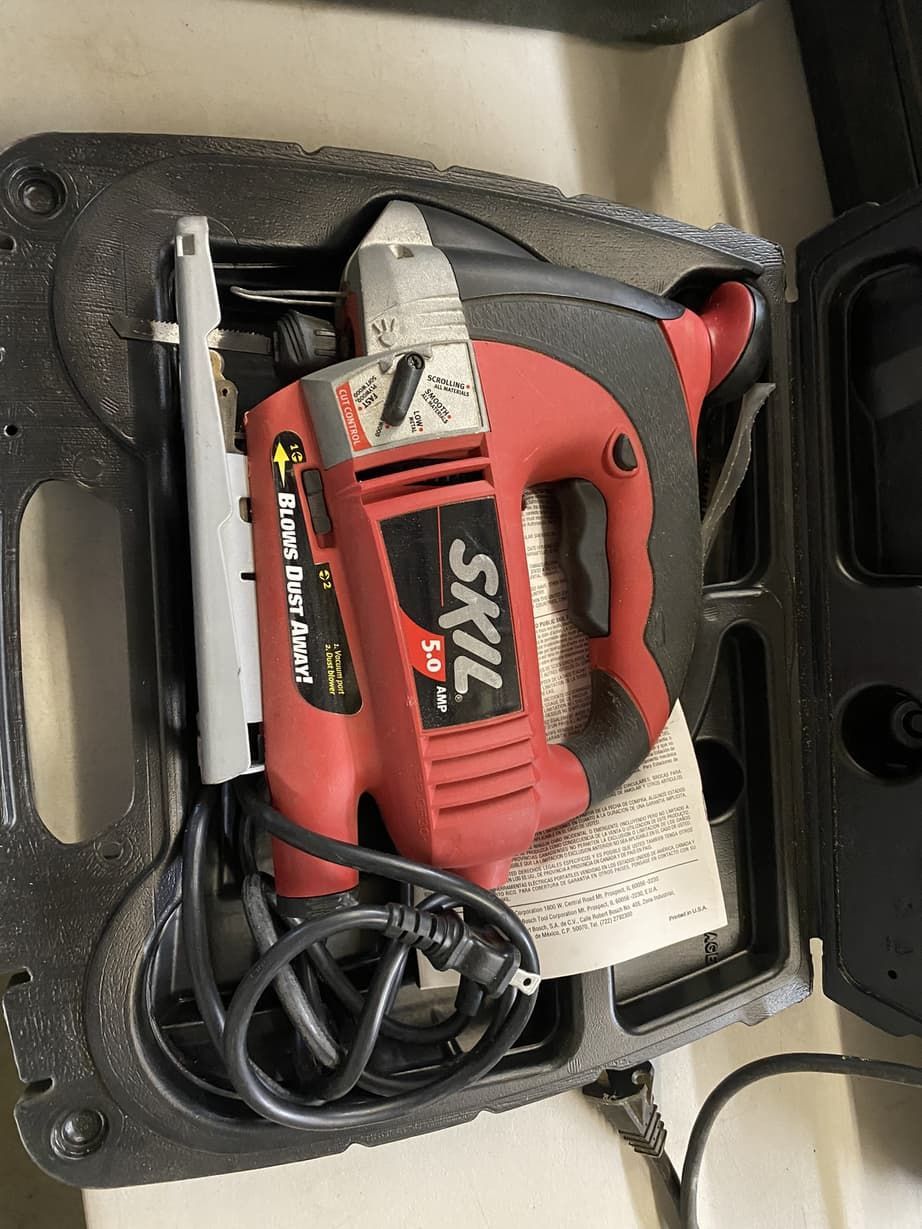 A red skil jigsaw is sitting in a case on a table.