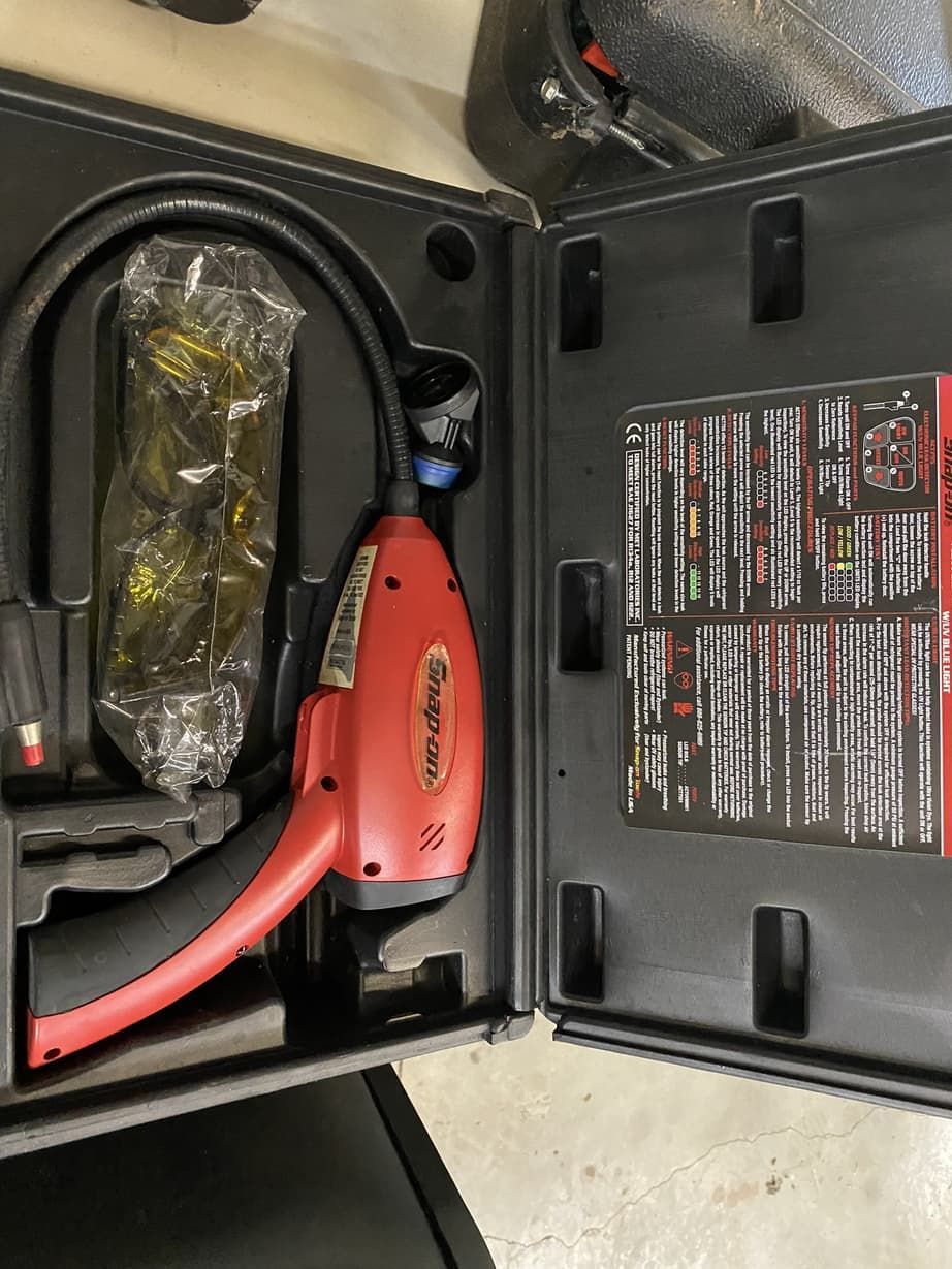 A red and black tool is in a black case.