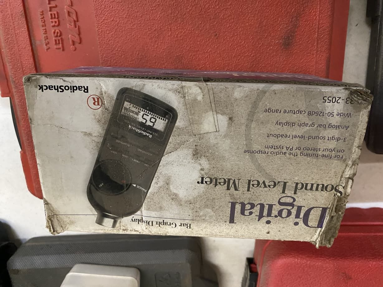 A digital sound level meter is in a box