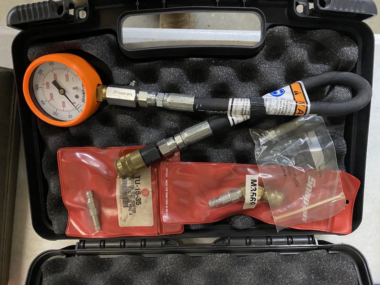 A pressure gauge is in a case with other tools