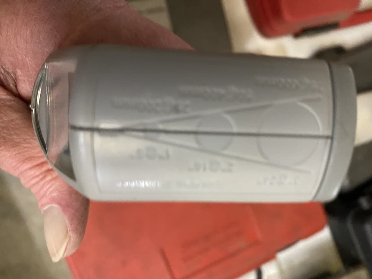 A person is holding a gray bottle in their hand.