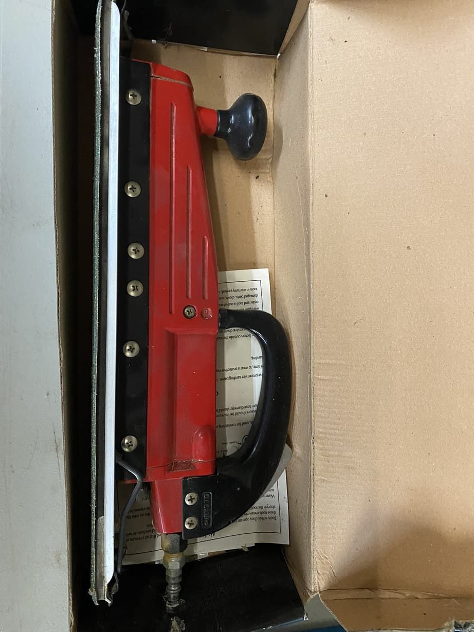 A red stapler is sitting in a cardboard box