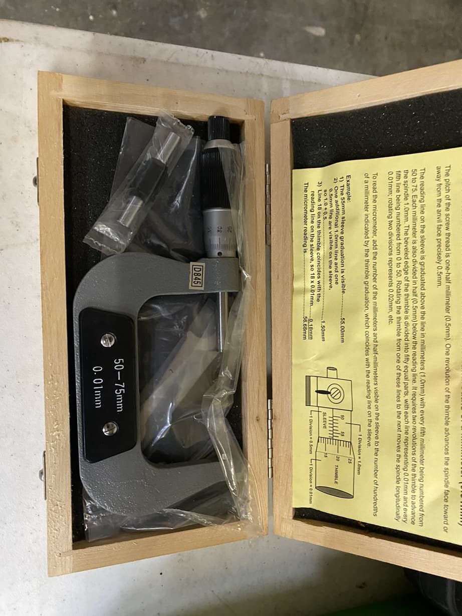 A micrometer is in a wooden box with instructions on it.