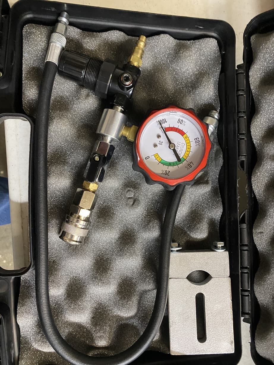 A hose with a gauge attached to it is in a case.