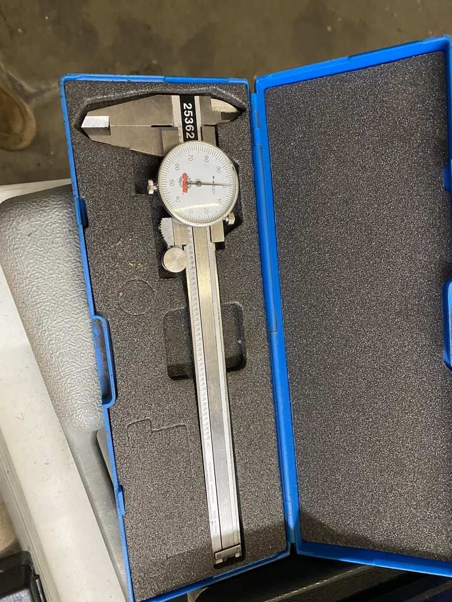 A caliper is sitting in a blue case on a table.