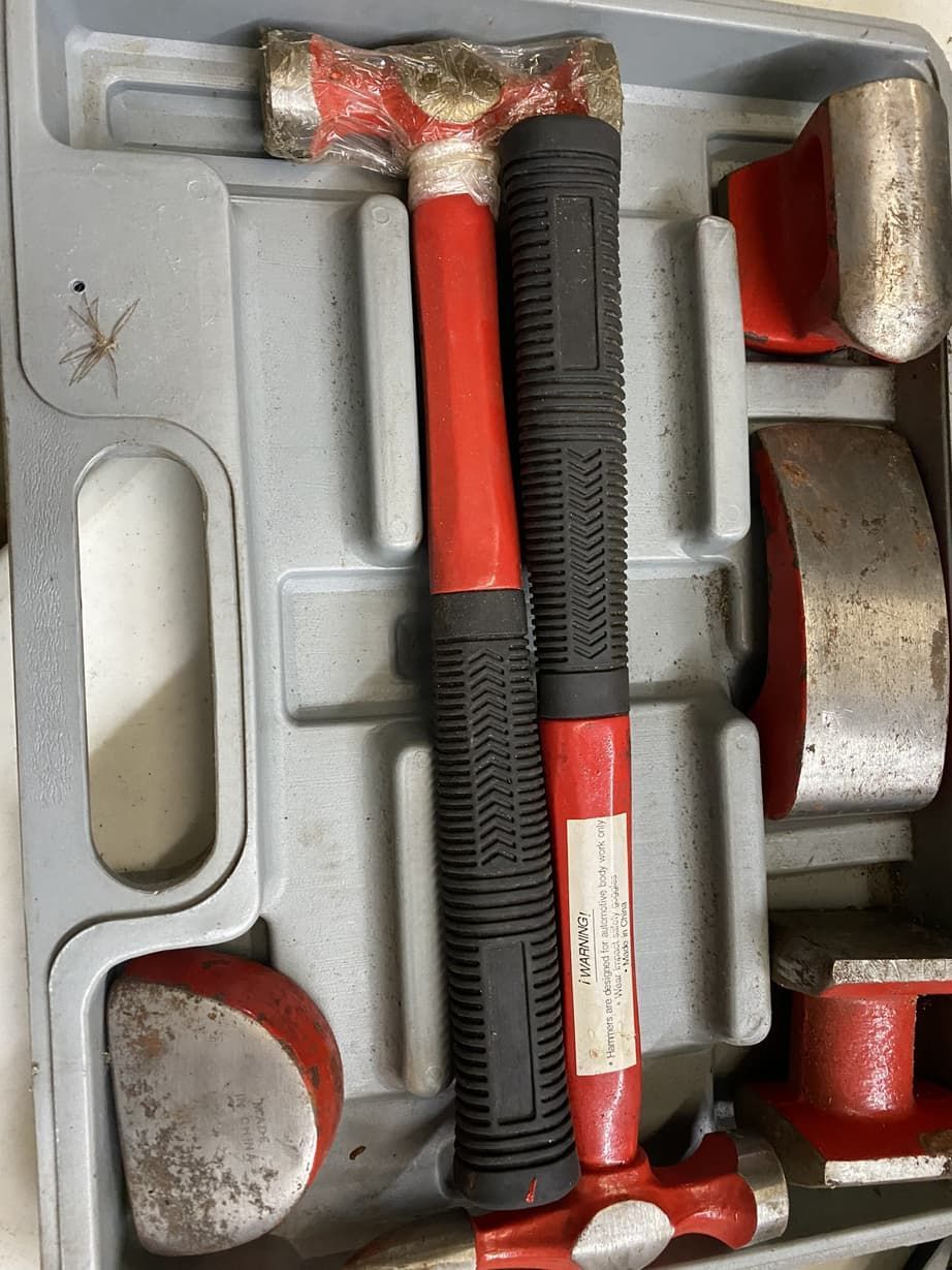 A hammer is sitting in a case with other tools.