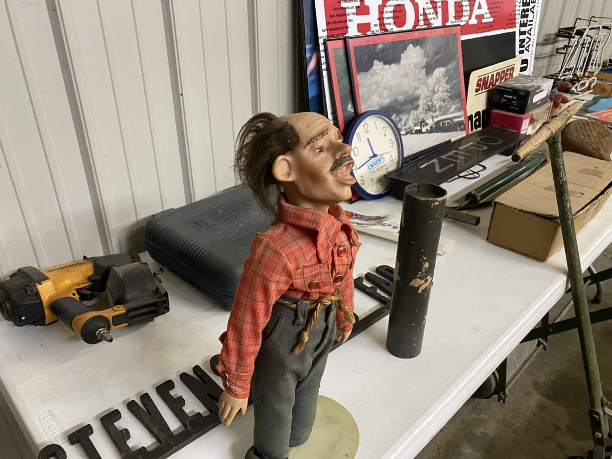 A statue of a man is sitting on a table next to a honda sign.