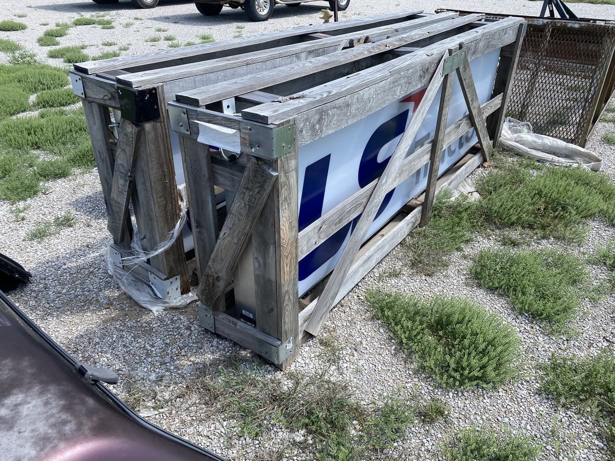 A large sign is sitting in a wooden box on the ground.