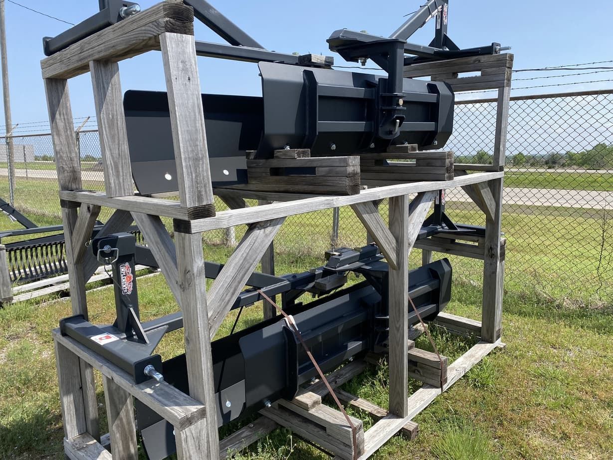 A wooden crate filled with tractor parts is sitting in the grass.