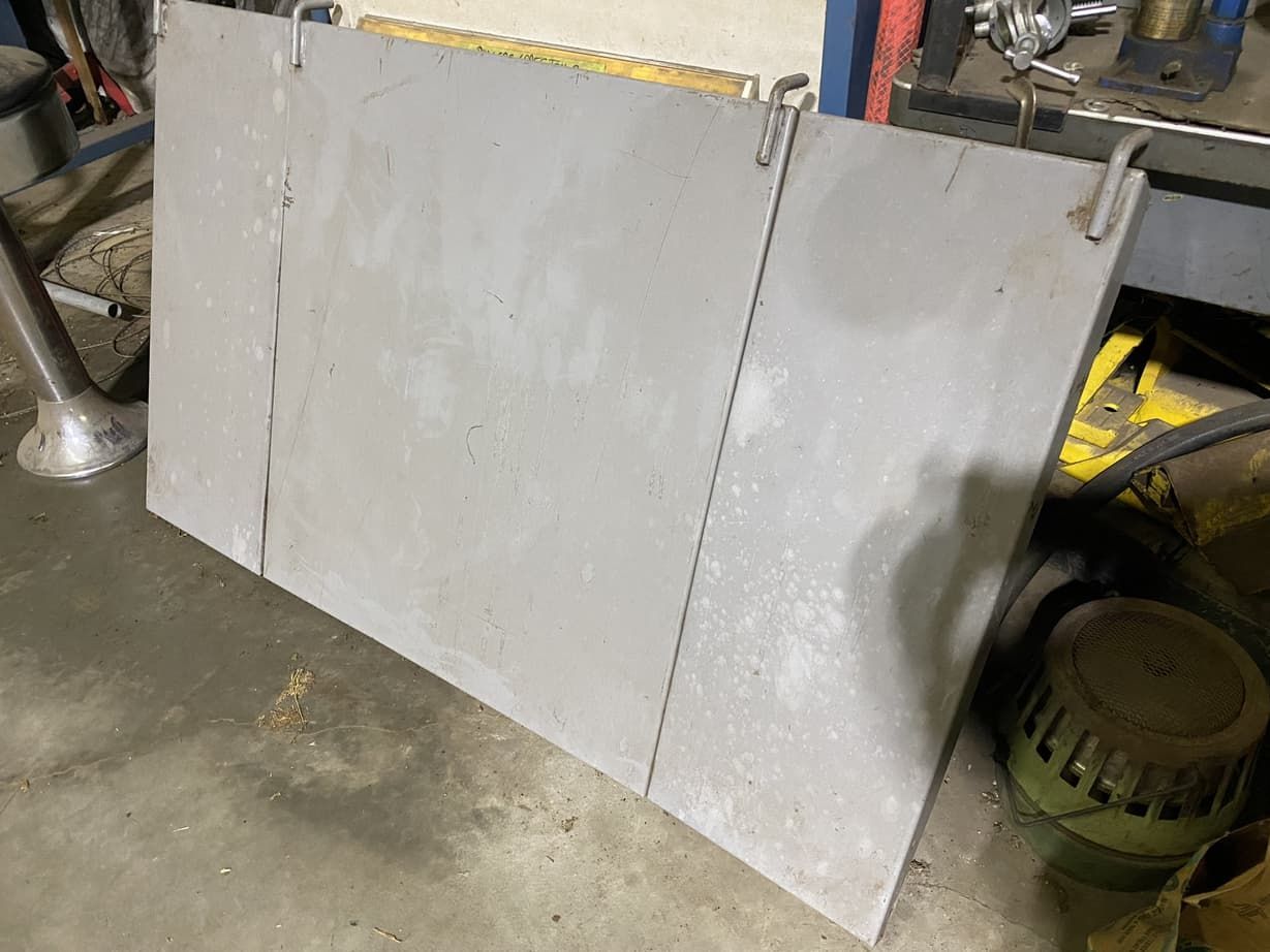 A large piece of metal is sitting on the floor next to a machine.