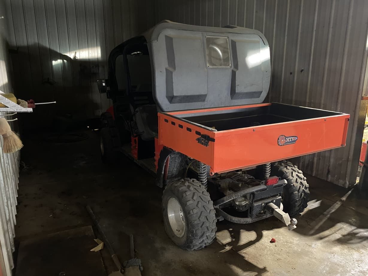 A utility vehicle with a cooler on the back is parked in a garage.