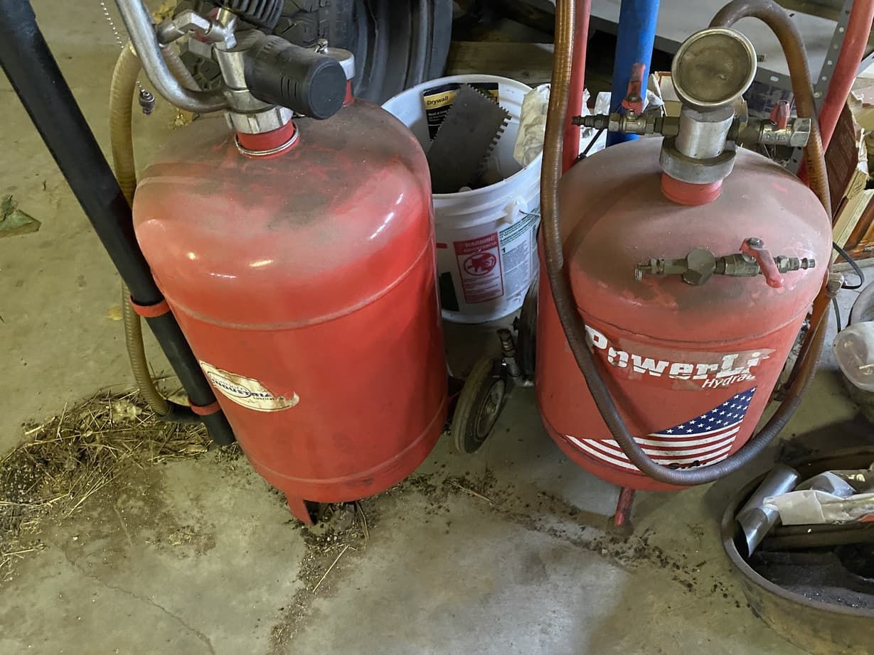 Two red fire extinguishers are sitting next to each other on the floor.