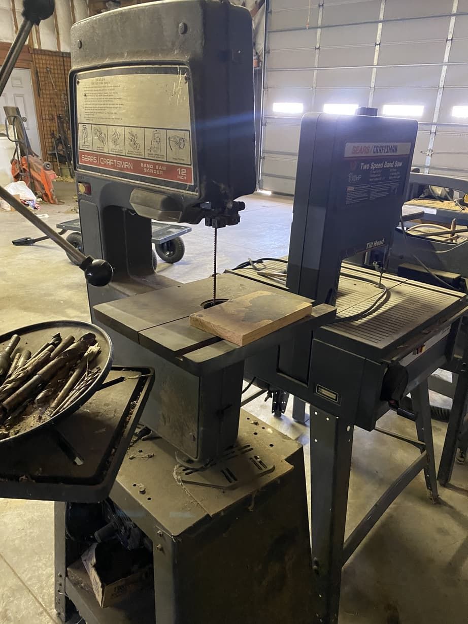 A band saw is sitting on top of a table in a garage.