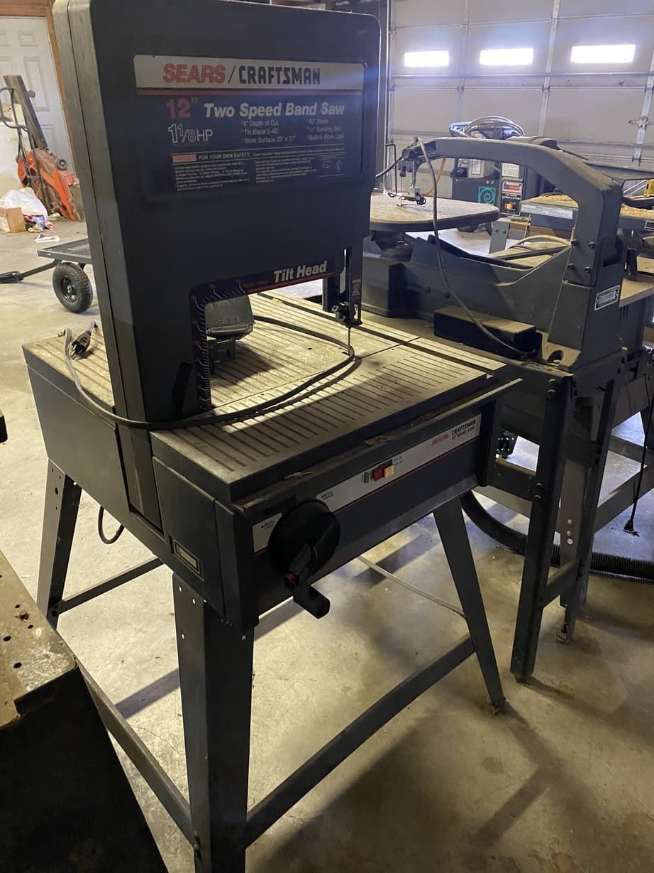 A band saw is sitting on top of a table in a garage.