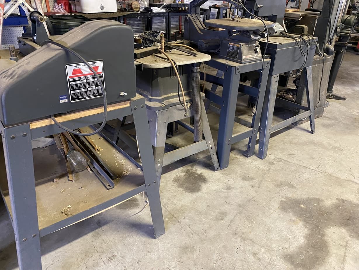 A row of machines are sitting on a concrete floor in a garage.