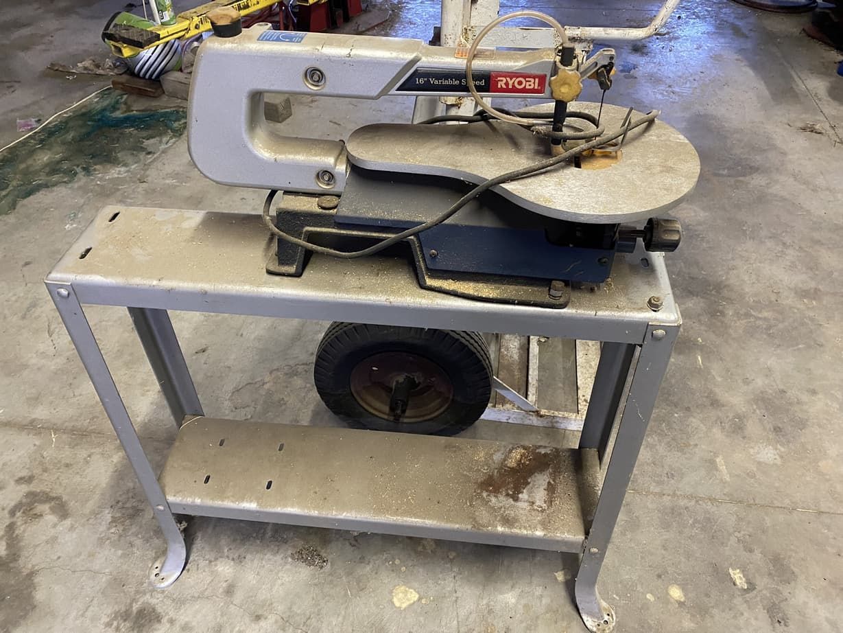 A saw is sitting on top of a metal table.