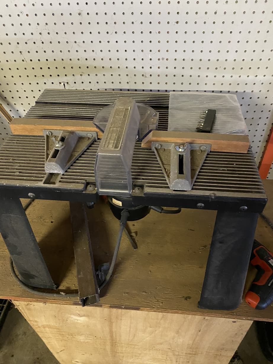 A table saw is sitting on top of a wooden table.