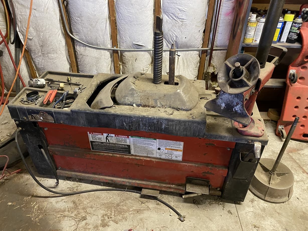 A red and black machine is sitting on the floor in a garage.