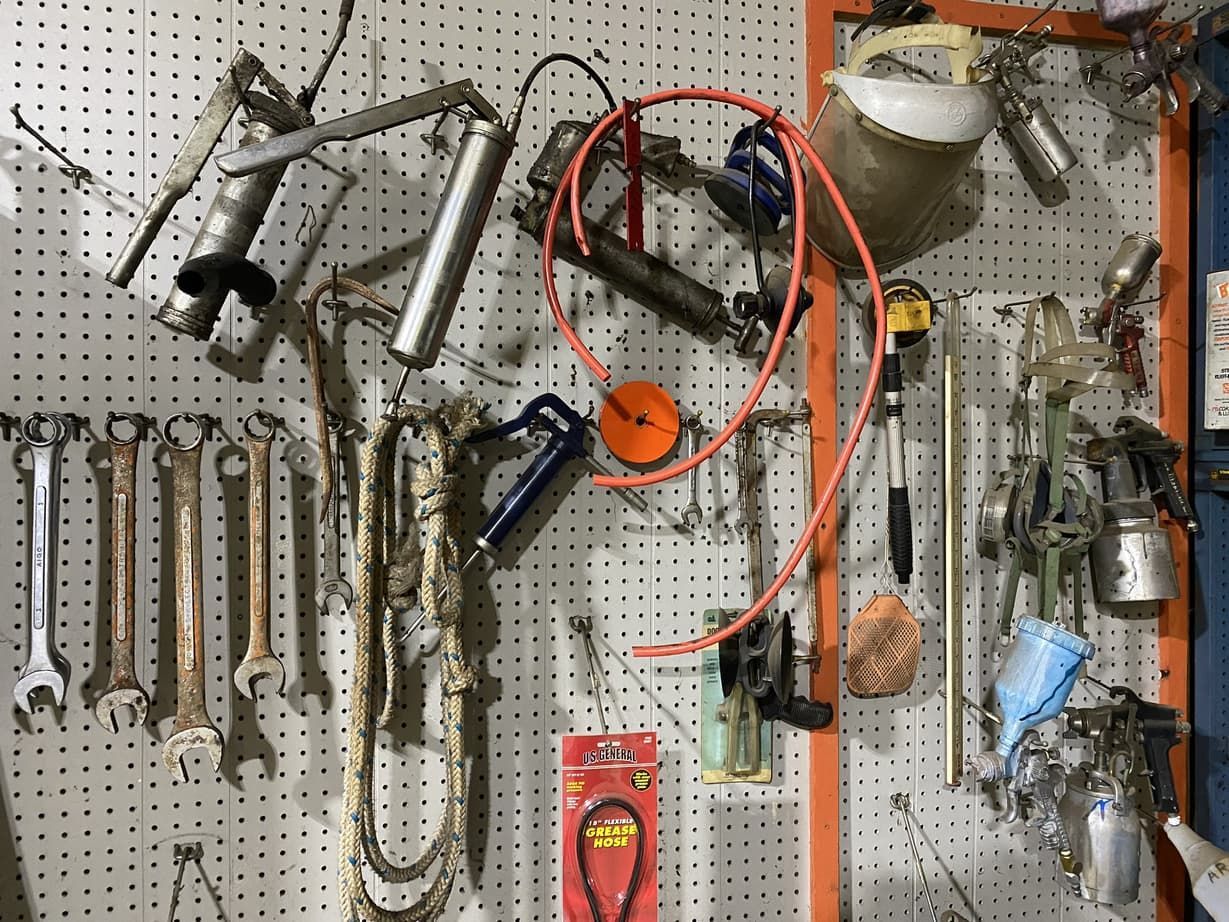 A bunch of tools are hanging on a wall.