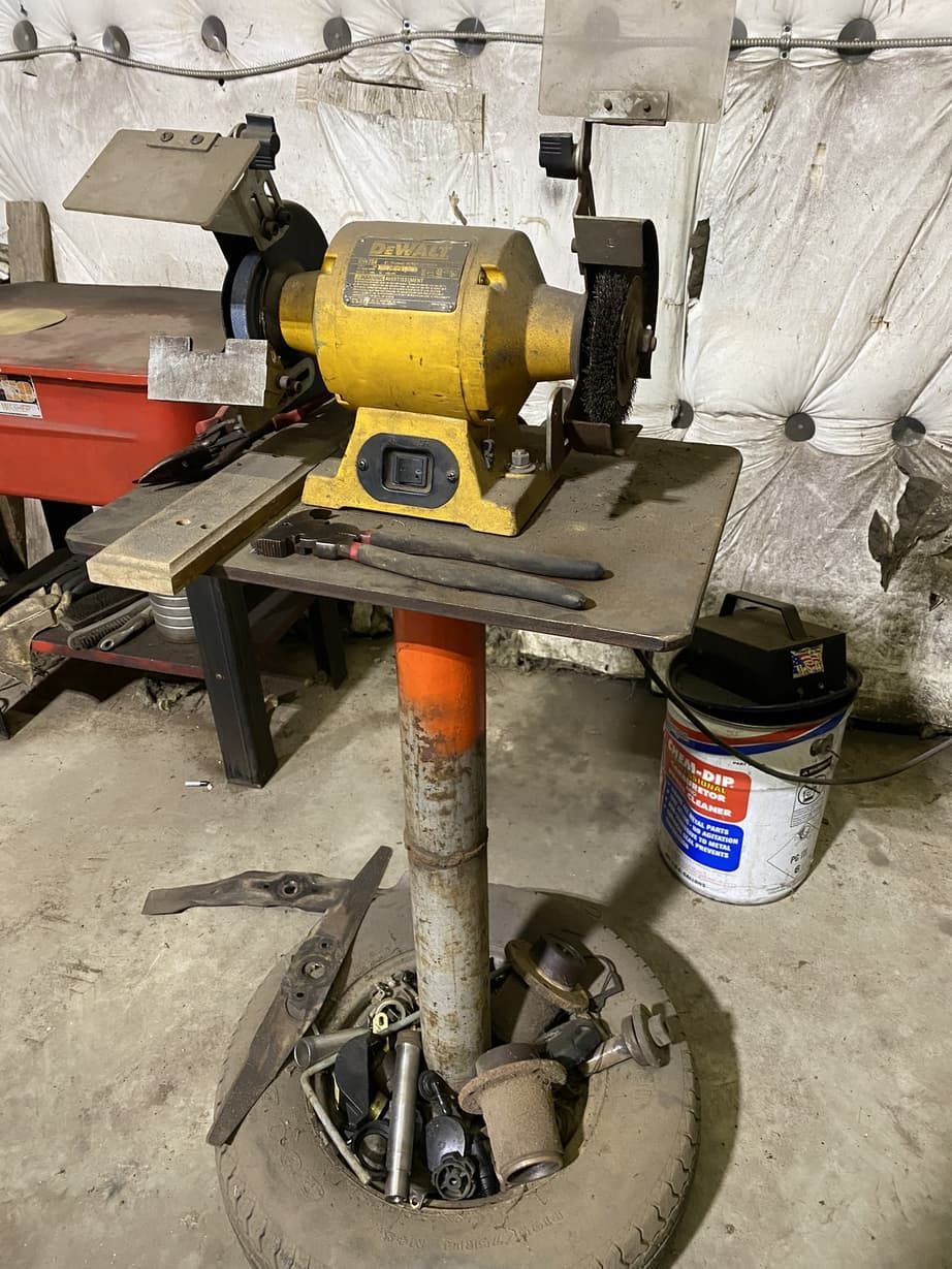 A grinder is sitting on top of a table in a garage.