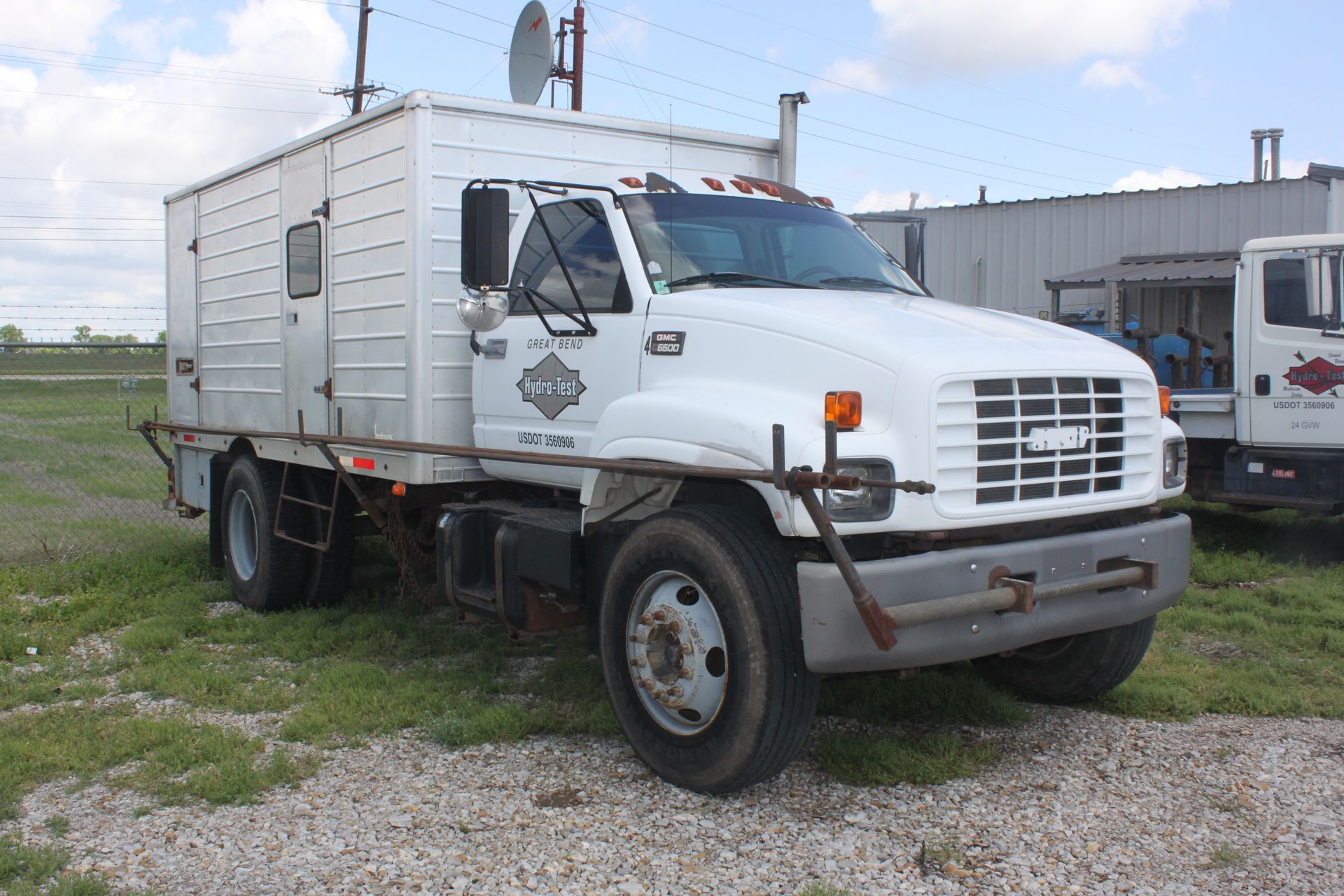 A white truck is parked in a gravel lot