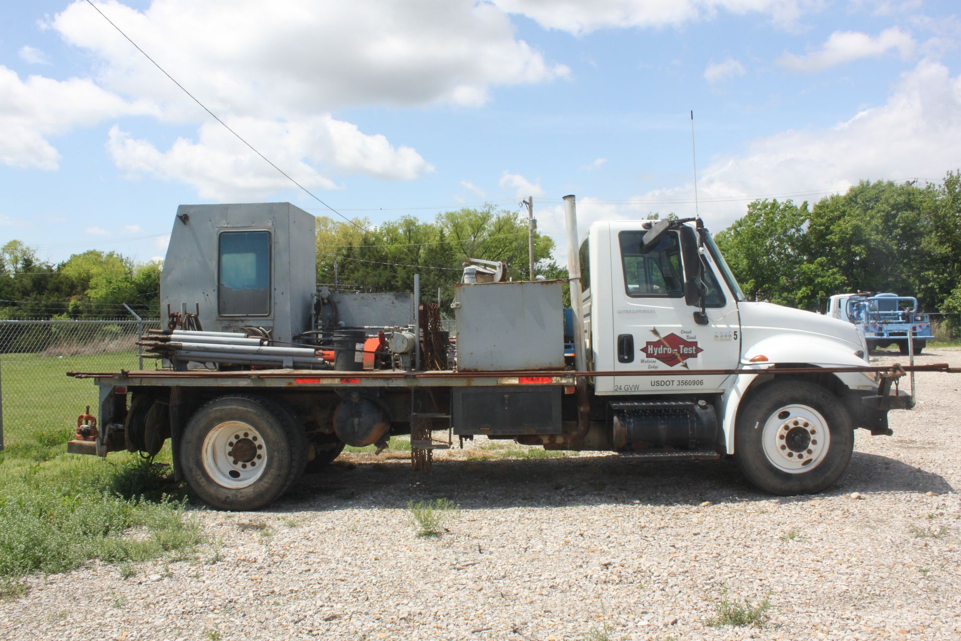 A white hydro test truck is parked in a gravel lot