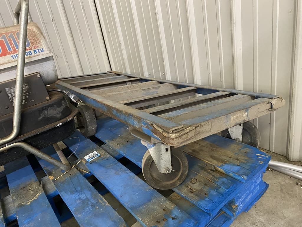 A cart is sitting on top of a stack of blue pallets.