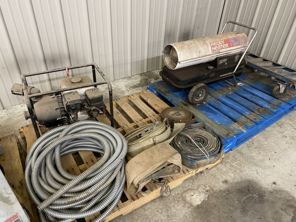 A hose is sitting on a wooden pallet next to a heater.