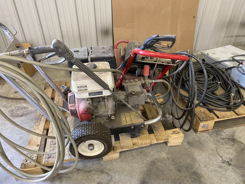 A pressure washer is sitting on top of a wooden pallet.
