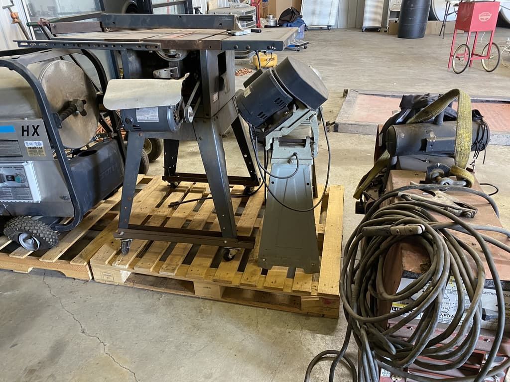 A table saw is sitting on top of a wooden pallet in a garage.