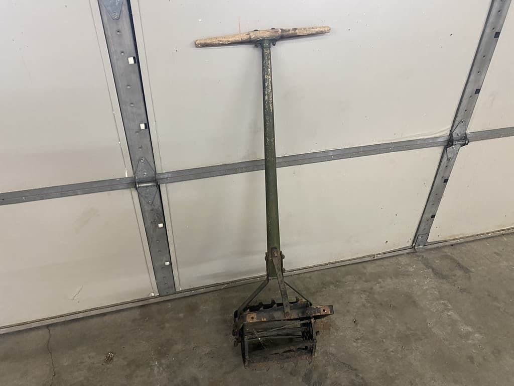 A tool with a wooden handle is sitting in front of a garage door.