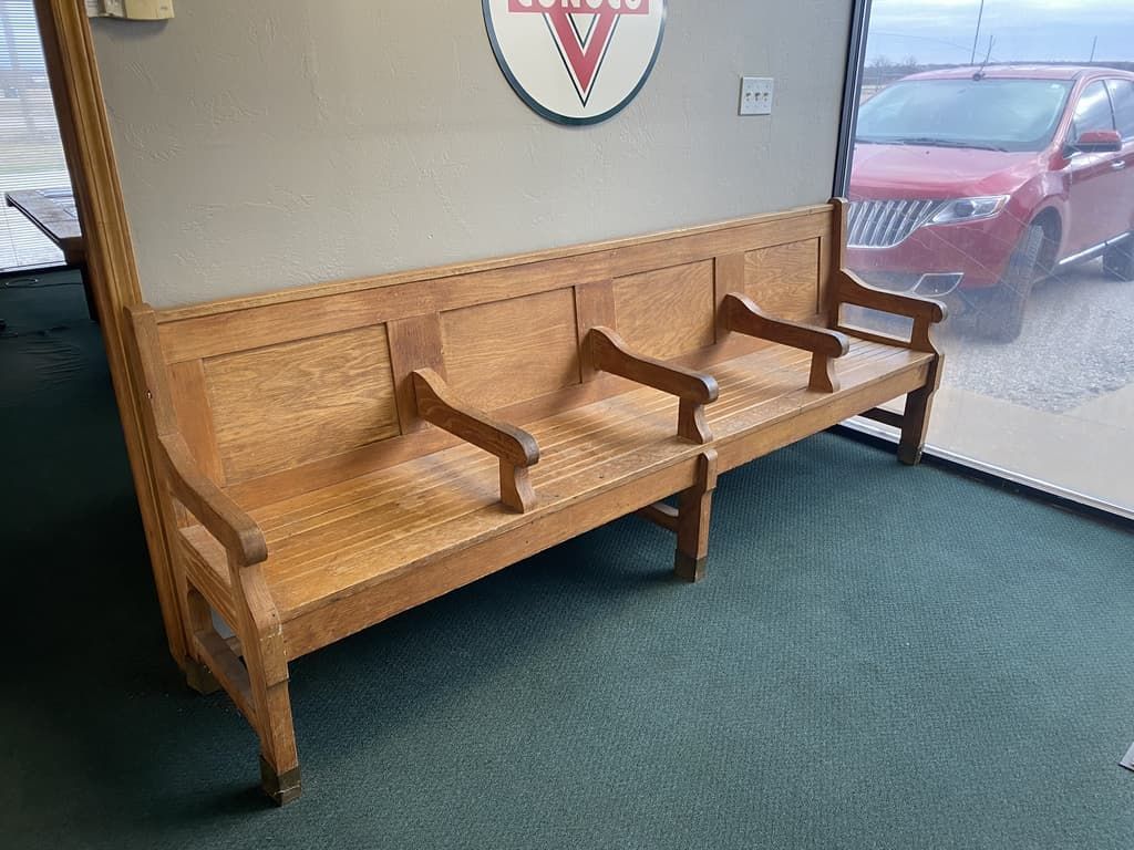 A wooden bench is sitting in a waiting room next to a window.