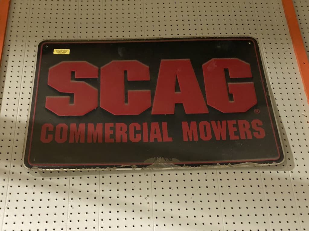A sign for scag commercial mowers hangs on a wall