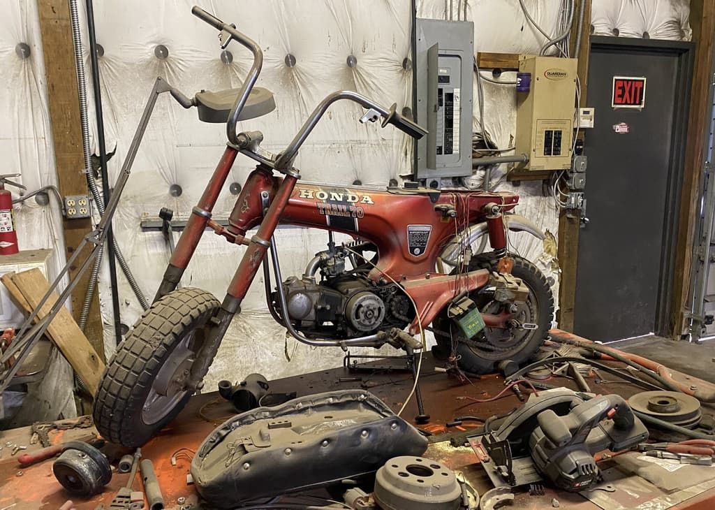 A red motorcycle is sitting on top of a table in a garage.