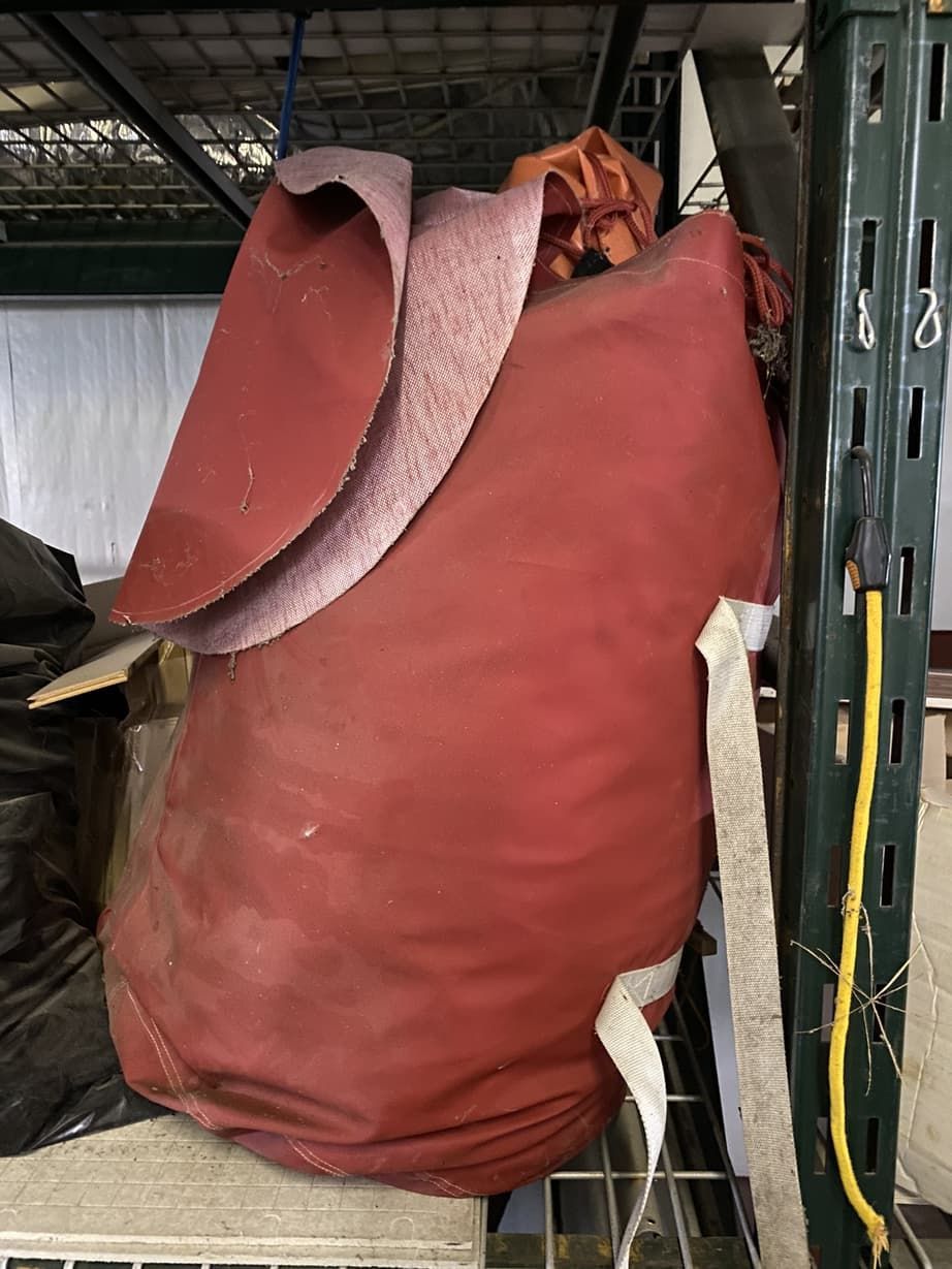 A large red bag is sitting on top of a shelf in a warehouse.