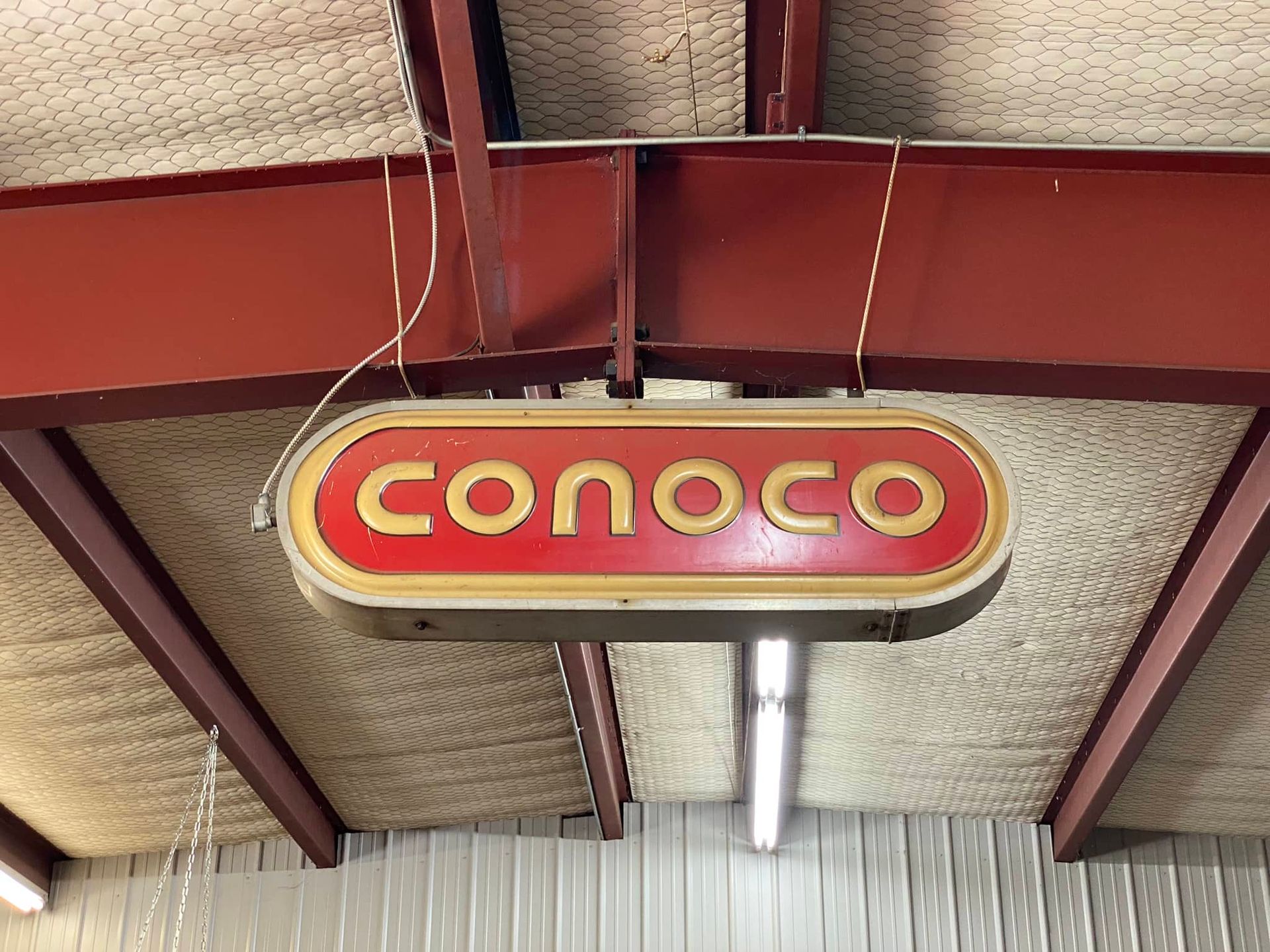 A conoco sign is hanging from the ceiling of a building