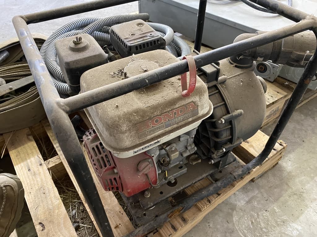 A gasoline engine is sitting on top of a wooden pallet.
