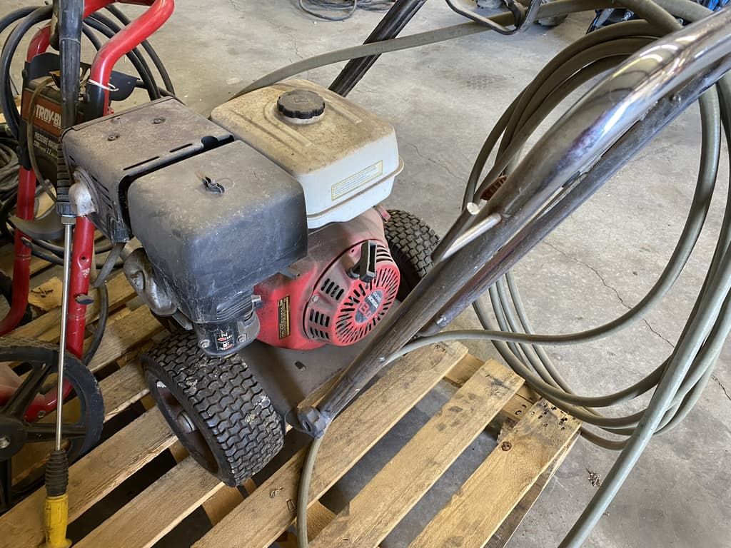 A gas powered pressure washer is sitting on top of a wooden pallet.