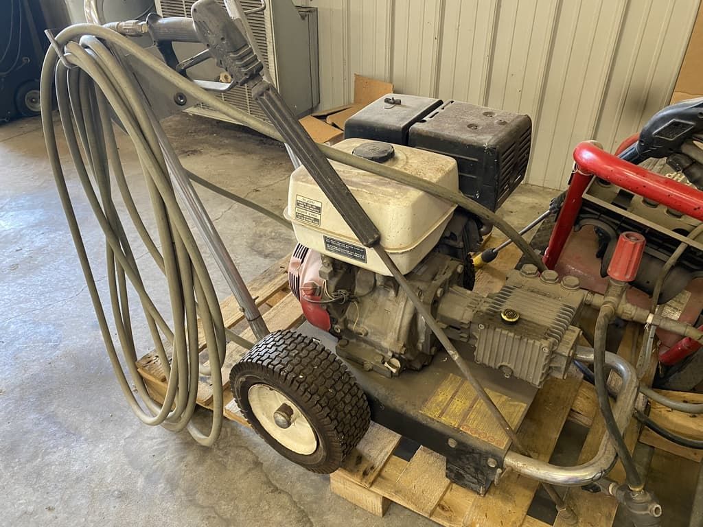 A high pressure washer is sitting on top of a wooden pallet.
