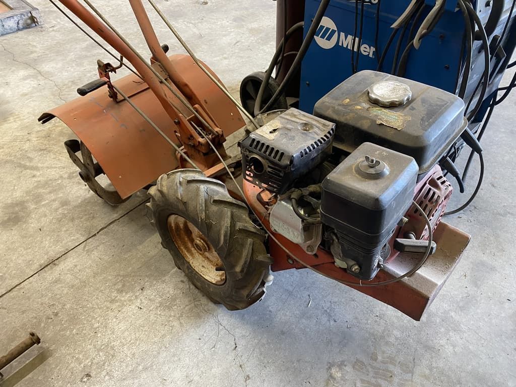 A small tractor with a welding machine in the background.