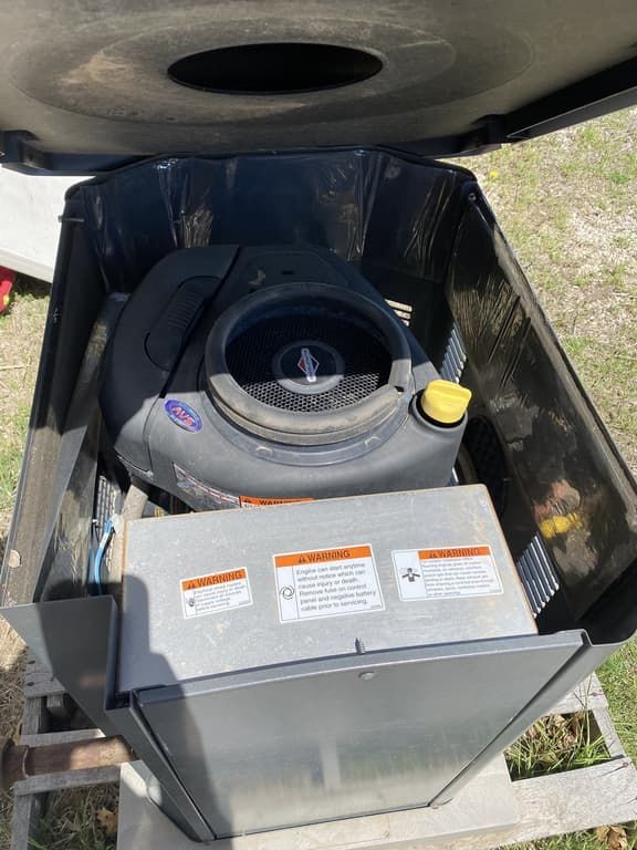 The engine of a lawn mower is sitting inside of a box.