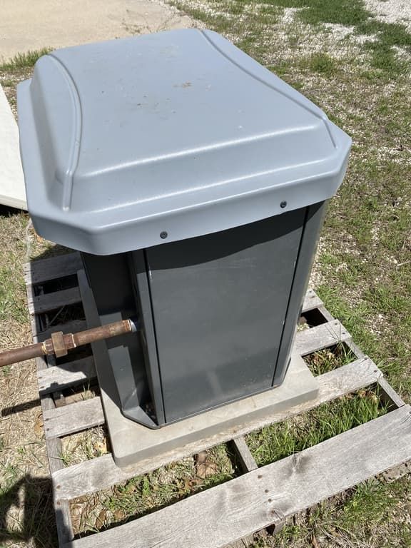 A gray trash can is sitting on a wooden pallet