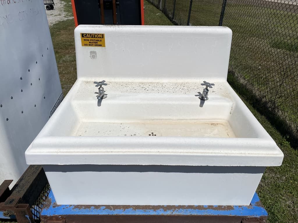 A white sink with a yellow warning sign on it