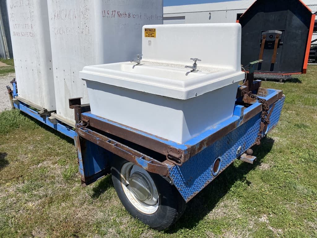 A trailer with a sink on it is parked in the grass.