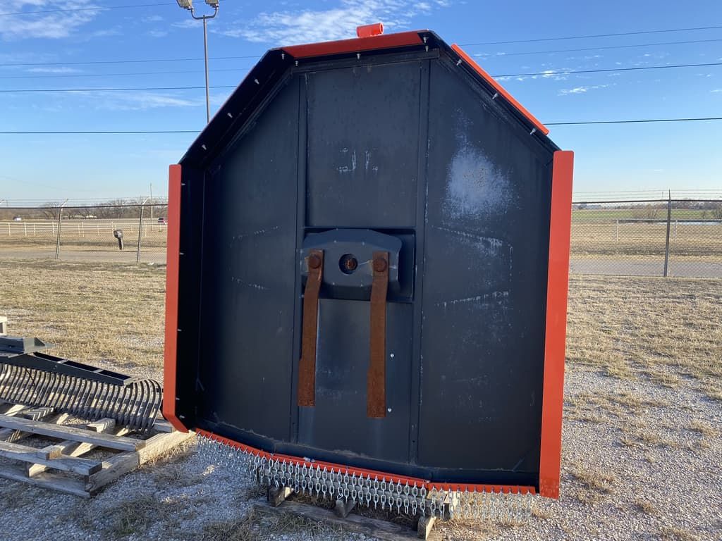 A black and red shed is sitting in the middle of a field.