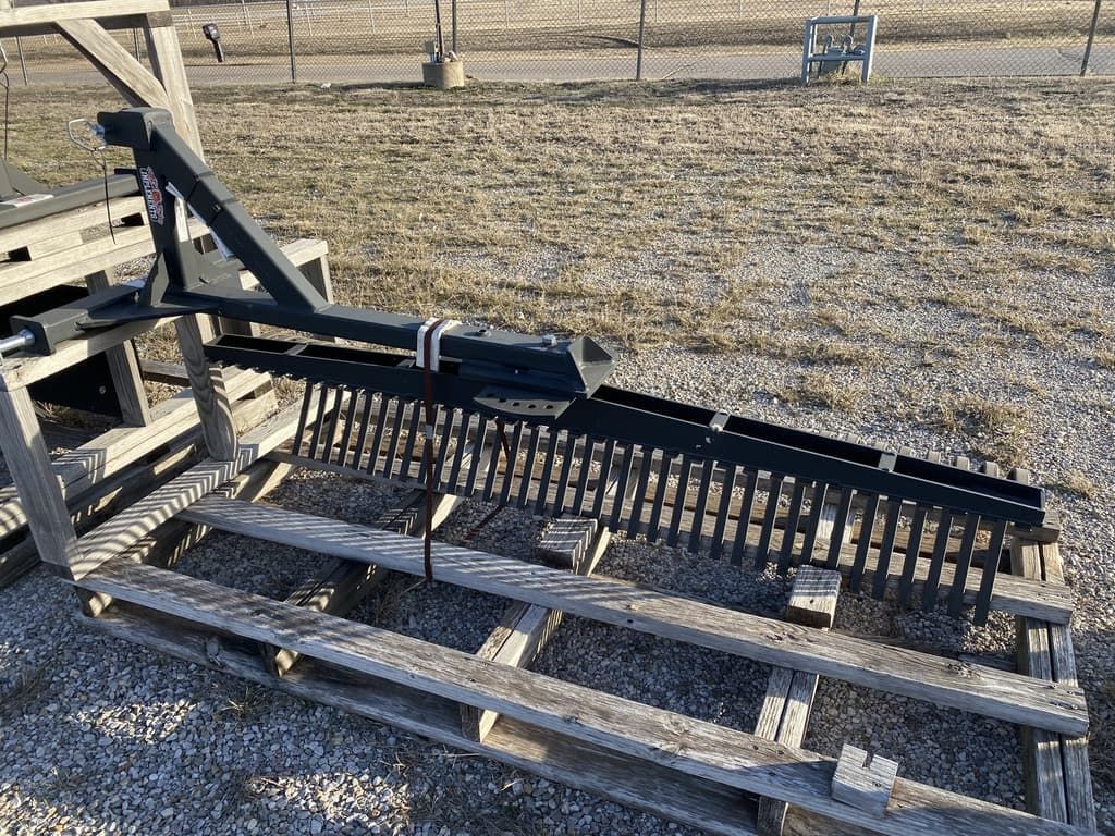 A rake is sitting on top of a wooden pallet in a field.