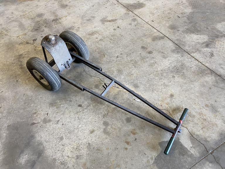 A metal cart with two wheels and a handle on a concrete floor