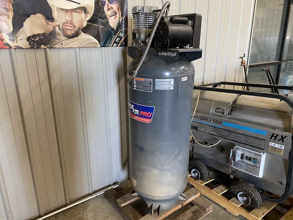 A large air compressor is sitting on a wooden pallet in a room.